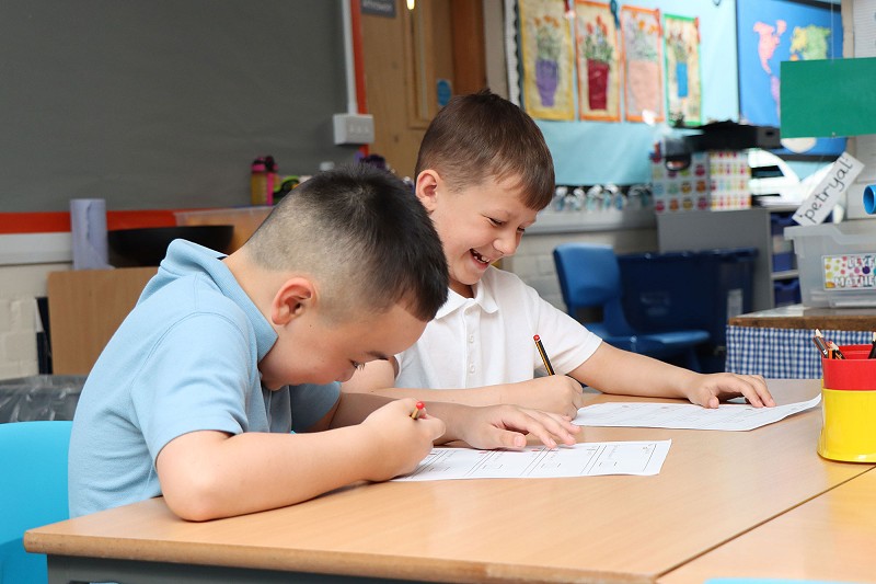 two ysgol Cymerau pupils laughing and working together